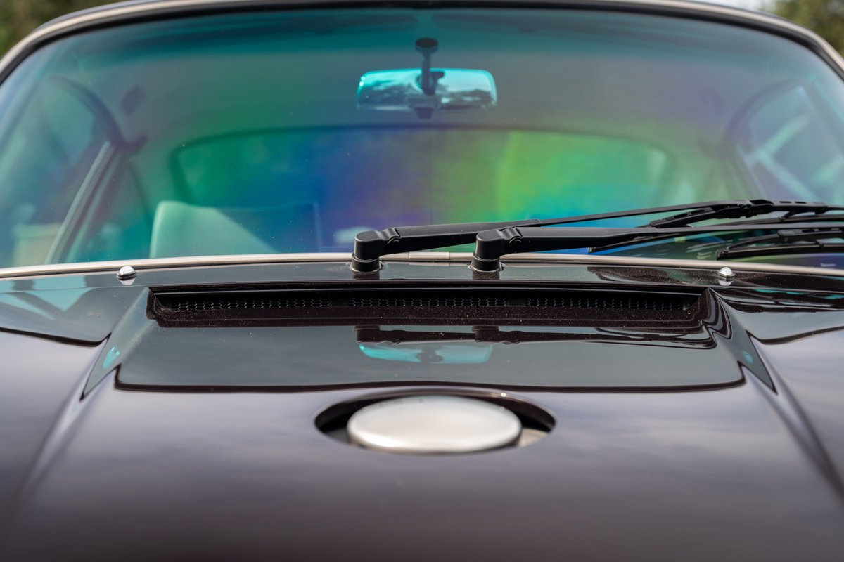 1990 Porsche 911 by Singer in aubergine metallic, close-up of windshield and hood detail.