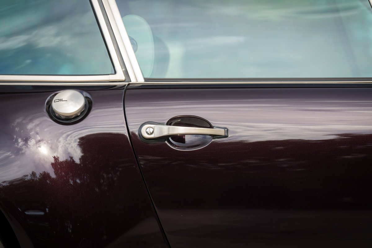 Aubergine metallic 1990 Singer 911 door with chrome trim, oil cap, and door handle.