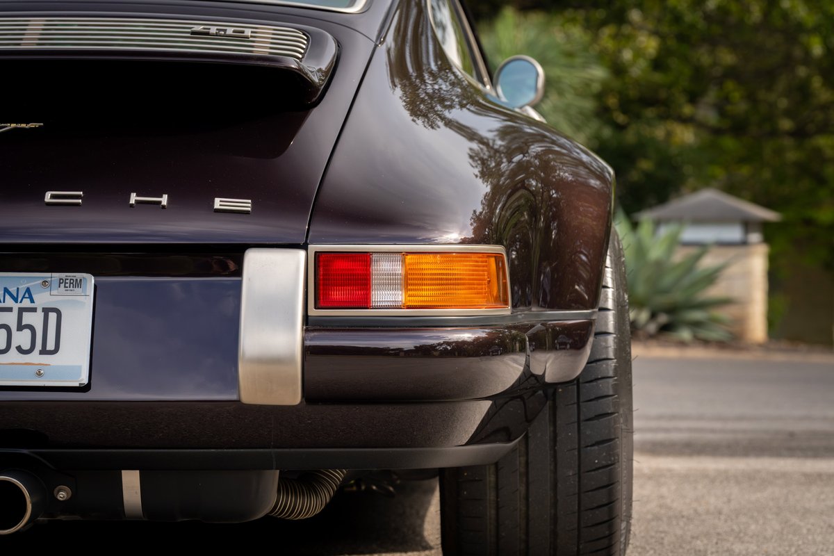 Aubergine metallic 1990 Singer Porsche 911, rear view, showing taillights, chrome trim, and exhaust.