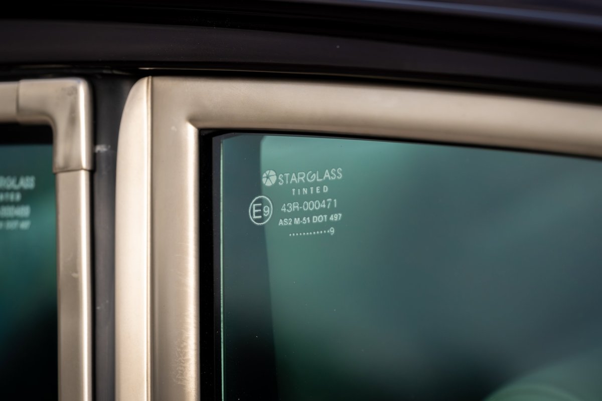 Close-up of aubergine metallic 1990 Singer Porsche 911 tinted window with StarGlass markings.