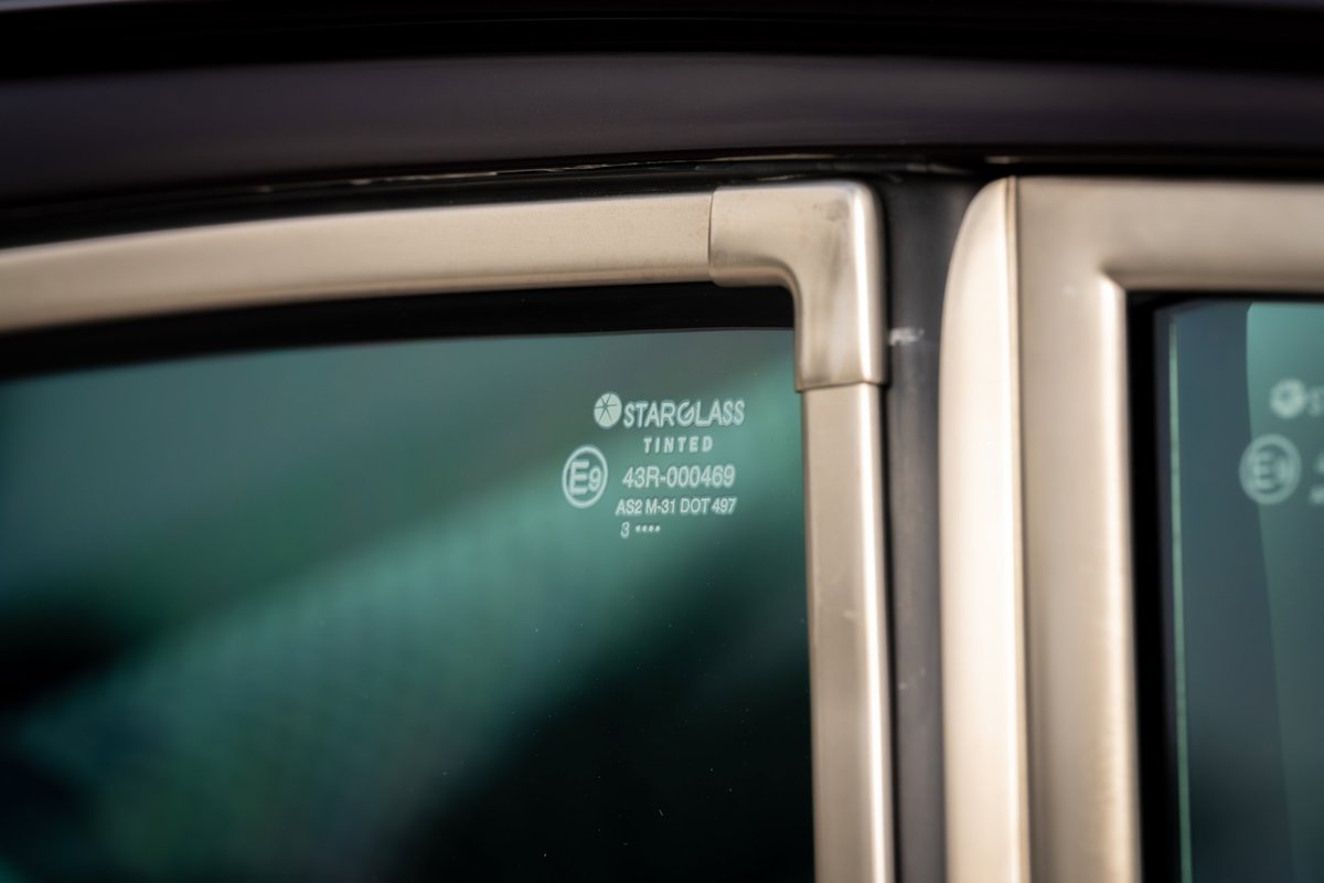Close-up of aubergine metallic 1990 Singer Porsche 911 tinted glass with Starglass logo.