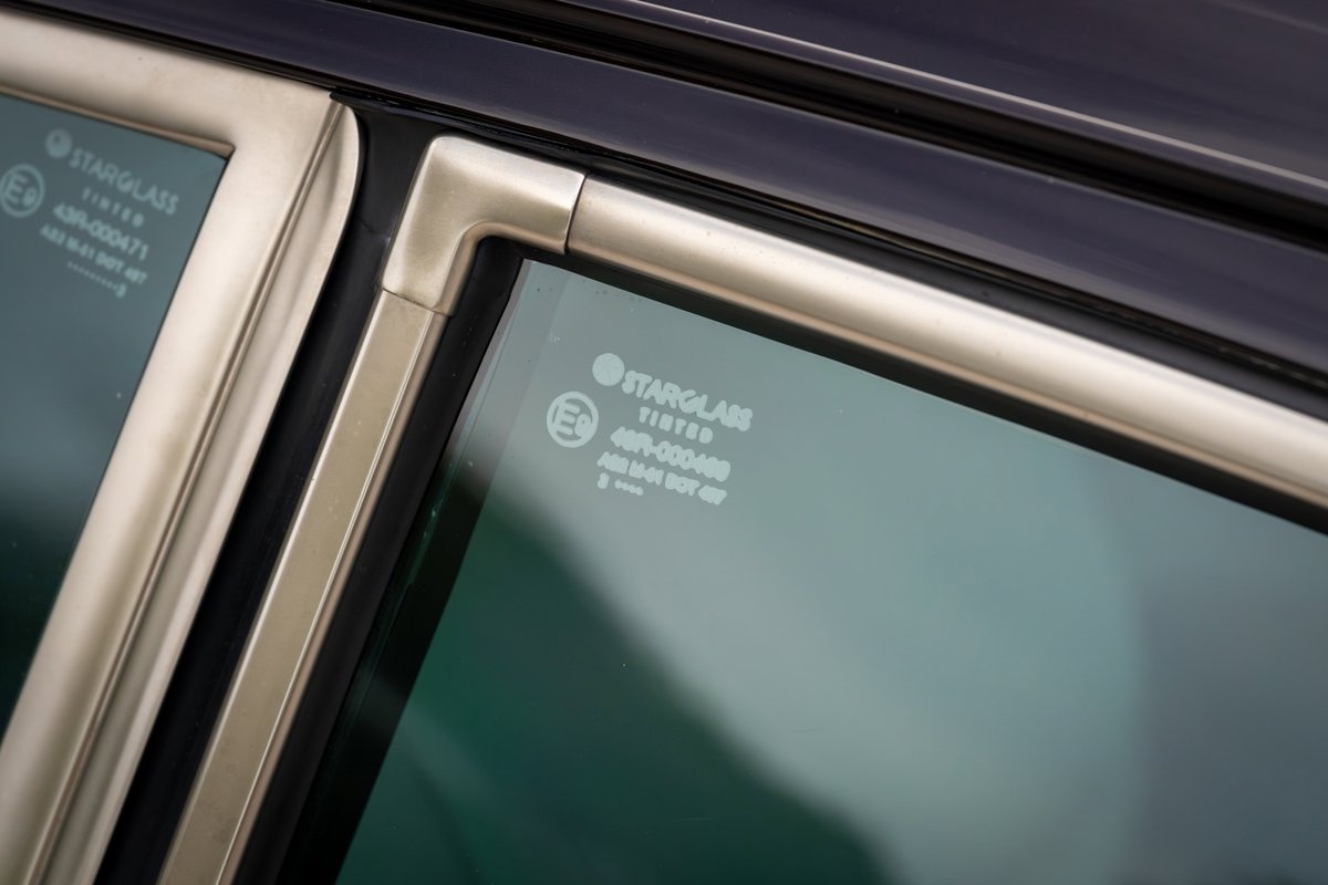 Close-up of a 1990 Singer Porsche 911's aubergine metallic door frame and tinted Starglass window.