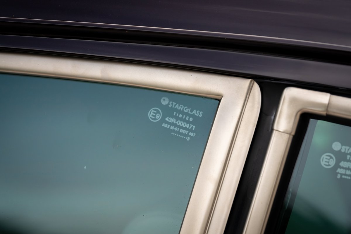 Close-up of tinted rear quarter glass with "STARGLASS TINTED" etching on a 1990 Aubergine Metallic Singer Porsche 911.