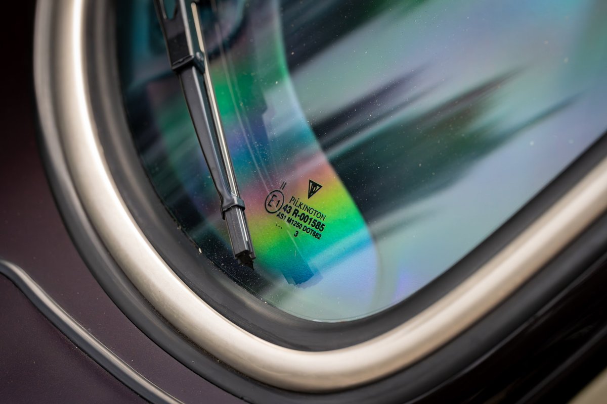 Close-up of a 1990 Singer Porsche 911 windshield with Pilkington glass markings and a wiper blade.