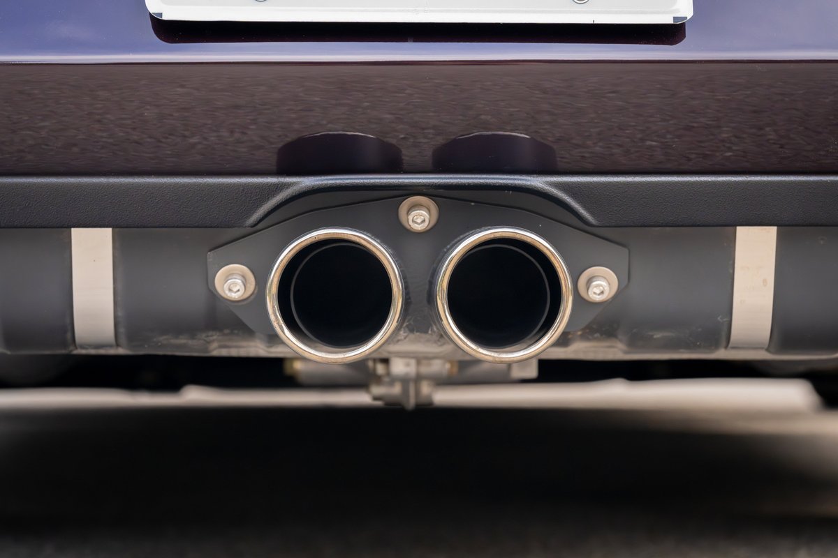 1990 Singer Porsche 911 in aubergine metallic, featuring quad exhaust tips.
