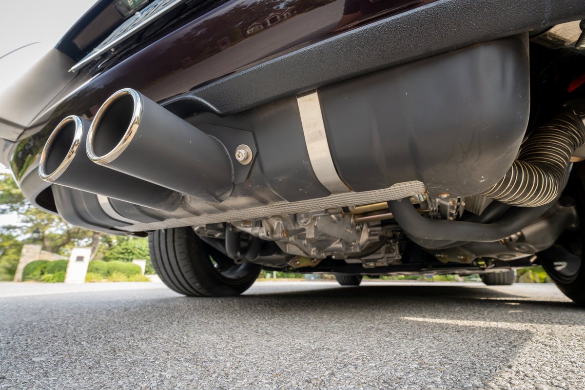 Dual chrome-tipped exhaust pipes on an aubergine metallic 1990 Singer Porsche 911.