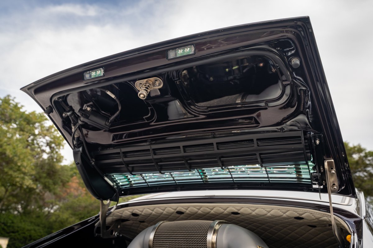 1990 Singer Porsche 911 aubergine metallic: open trunk lid, detail of latch and luggage compartment.