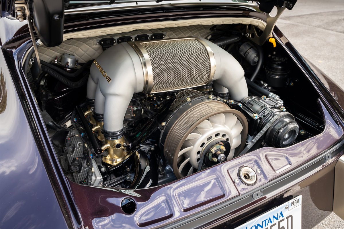 Singer Porsche 911 engine bay in aubergine metallic. Custom intake, fan, and cooling components are visible.