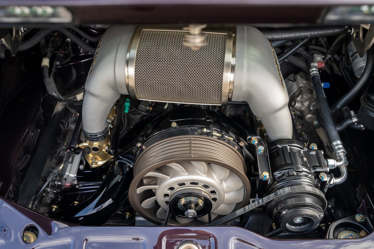 Aubergine metallic 1990 Singer 911 engine bay. Turbocharged flat-six engine with polished intake piping and mesh air filter.