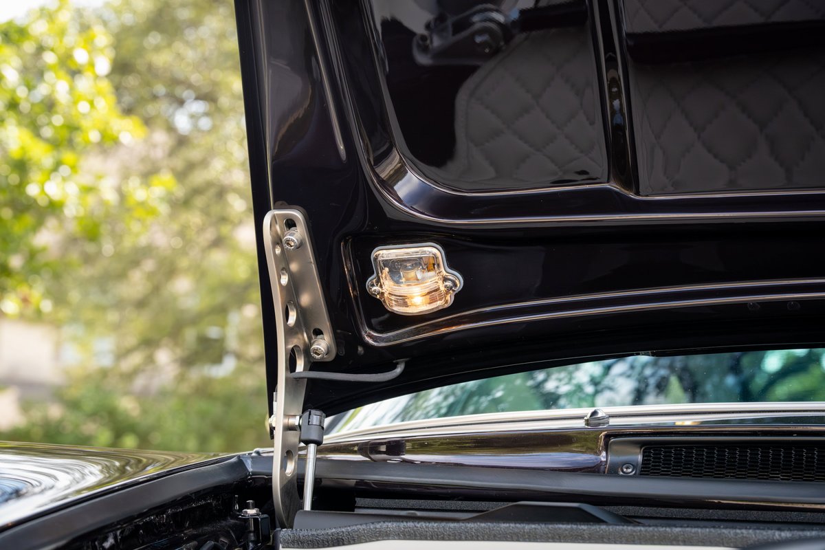 1990 Singer Porsche 911's hood light illuminates the aubergine metallic paint and polished hinge.