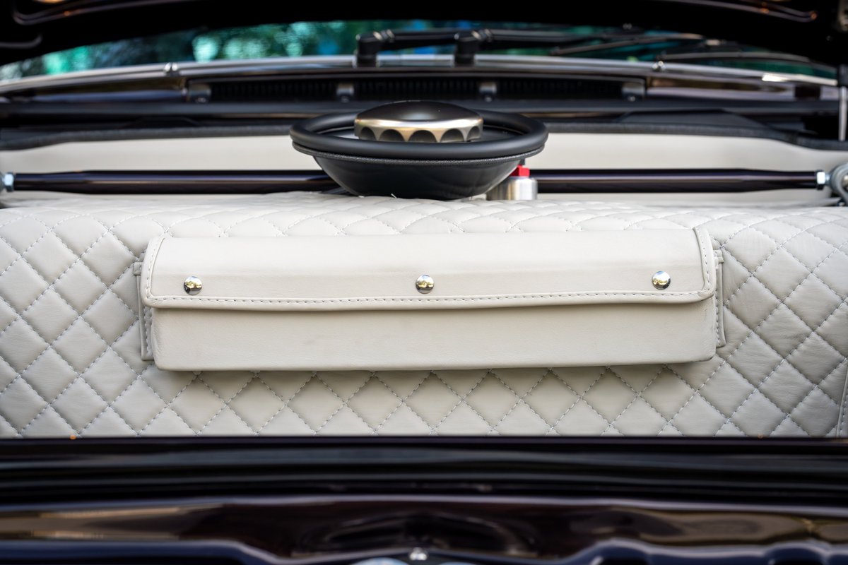 Close-up of a quilted interior of a 1990 aubergine metallic Singer Porsche 911 with a leather storage pouch.