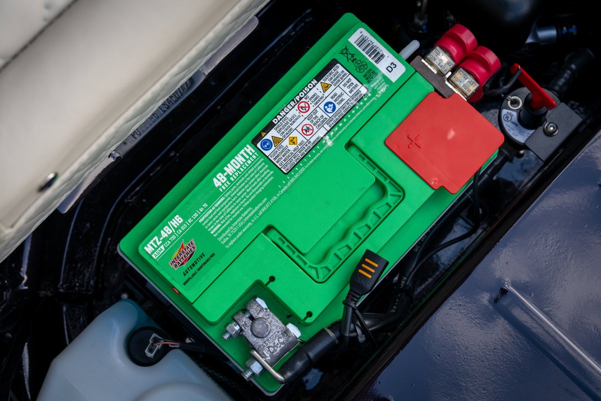 A green 1990 Singer Porsche 911 battery, labeled MTZ-4B/H6, with red terminal covers.