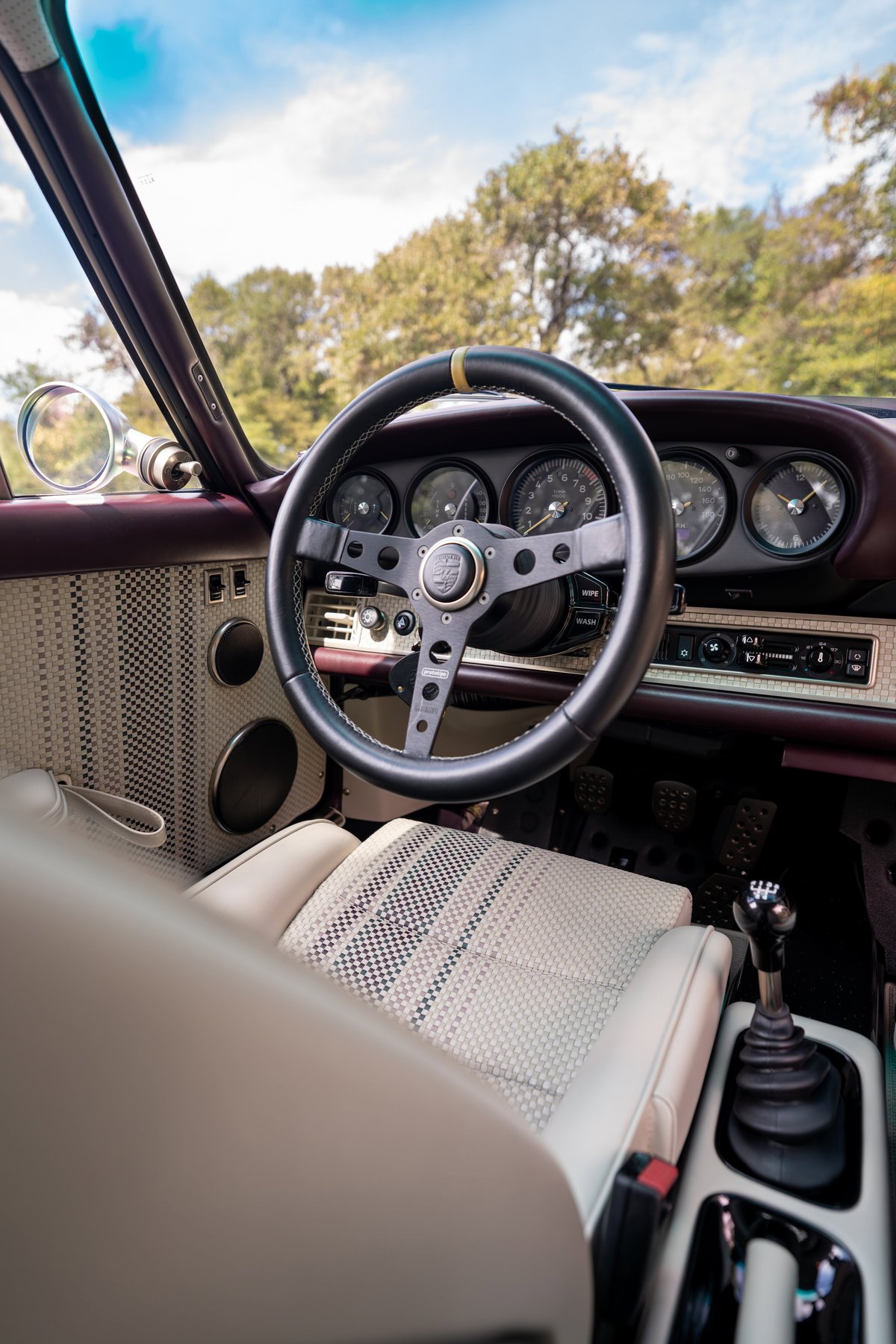 1990 Singer 911 interior. Aubergine metallic exterior, checkered seats, vintage steering wheel.