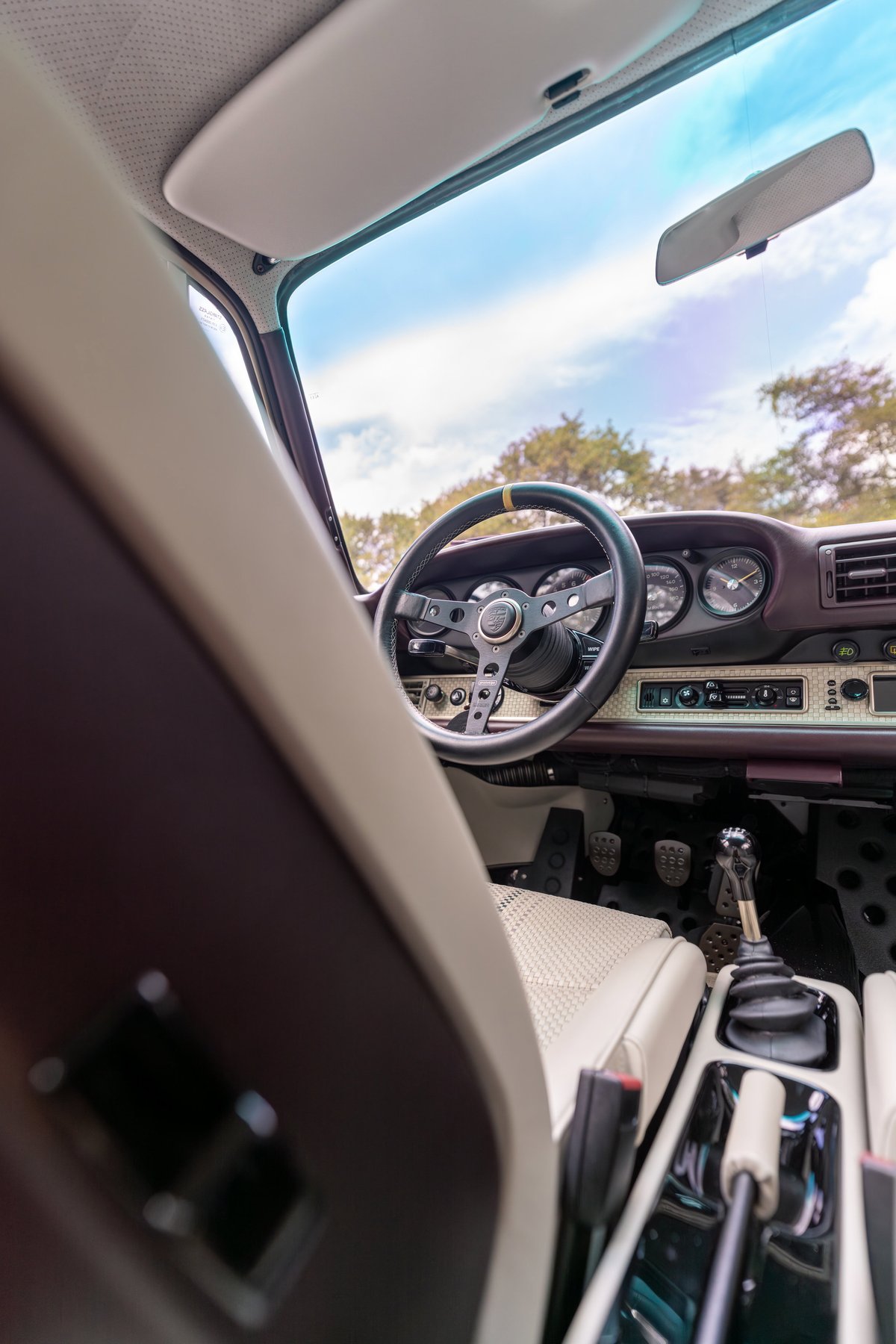 Singer 911 interior: aubergine metallic dash trim, bespoke steering wheel, perforated tan seats, 5-speed shifter.
