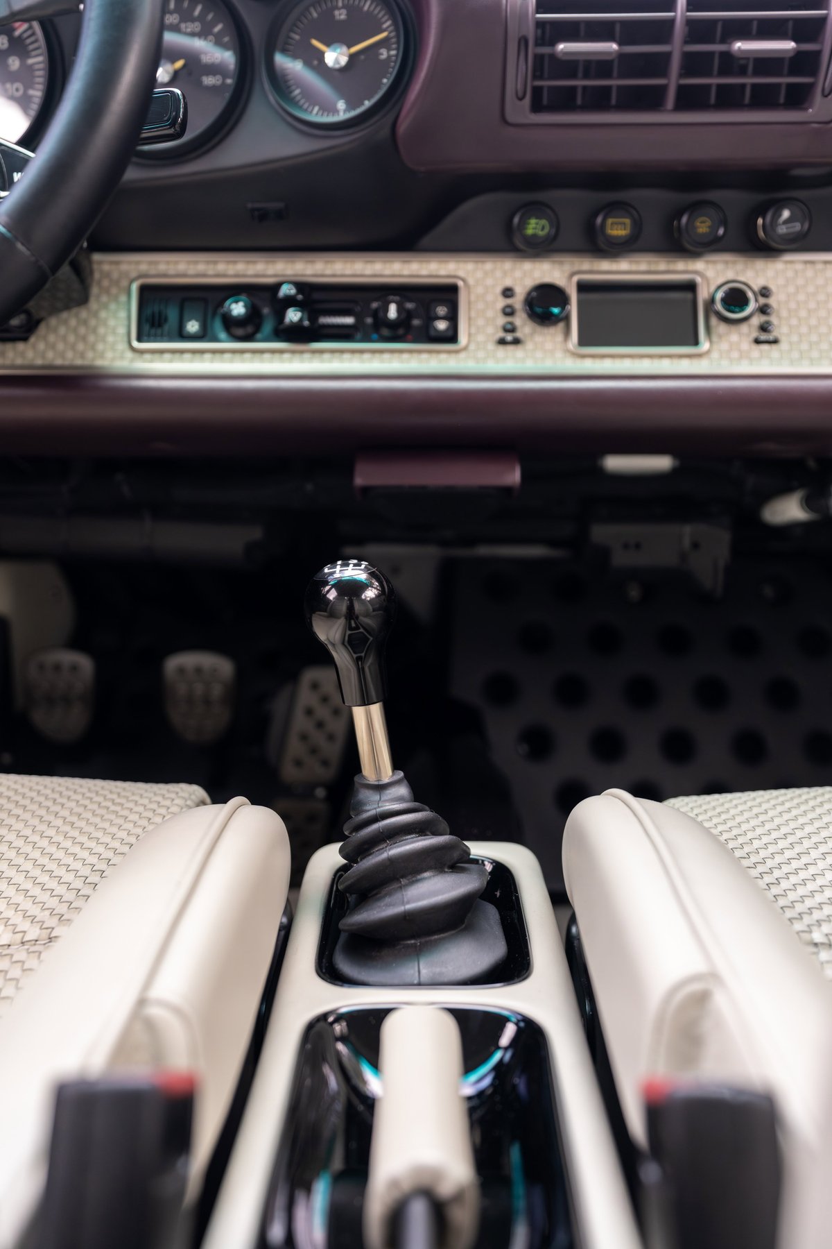 1990 Singer Porsche 911 interior, aubergine metallic, with 5-speed manual shifter and leather trim.
