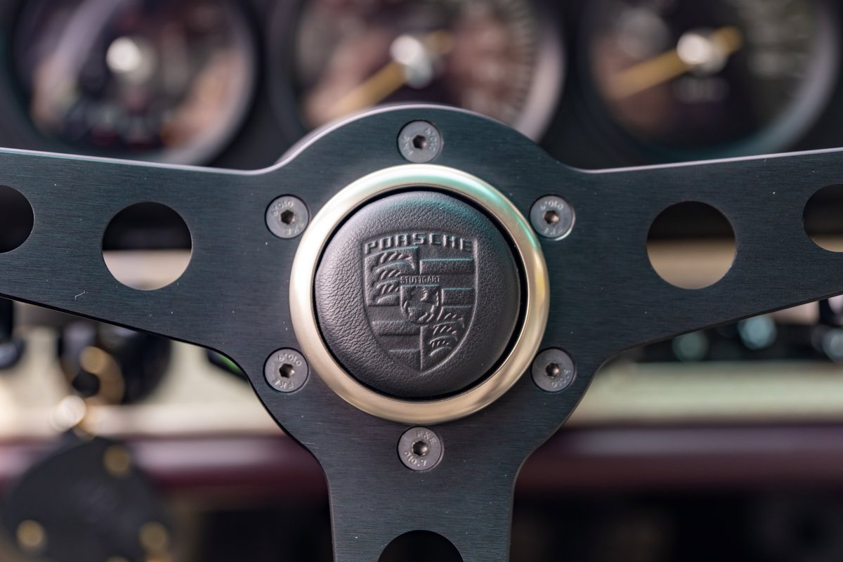 Close-up of a 1990 Singer Porsche 911 steering wheel with Porsche crest.