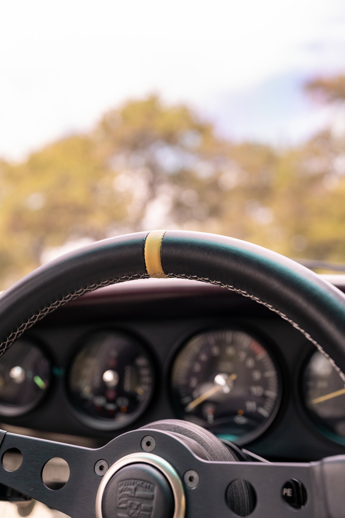1990 Singer Porsche 911 interior: close-up on steering wheel with yellow 12 o'clock marker.
