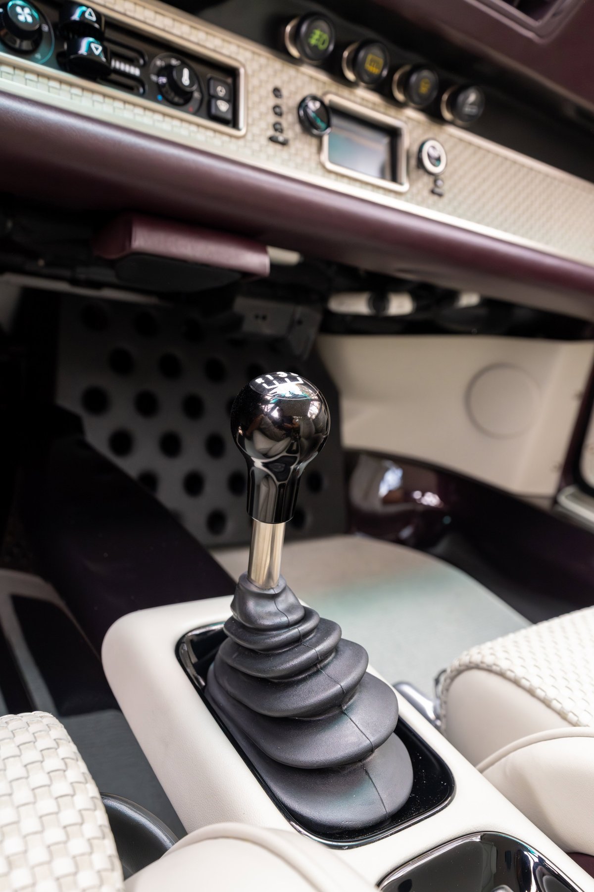 1990 Singer Porsche 911 in aubergine metallic with a black shift knob.