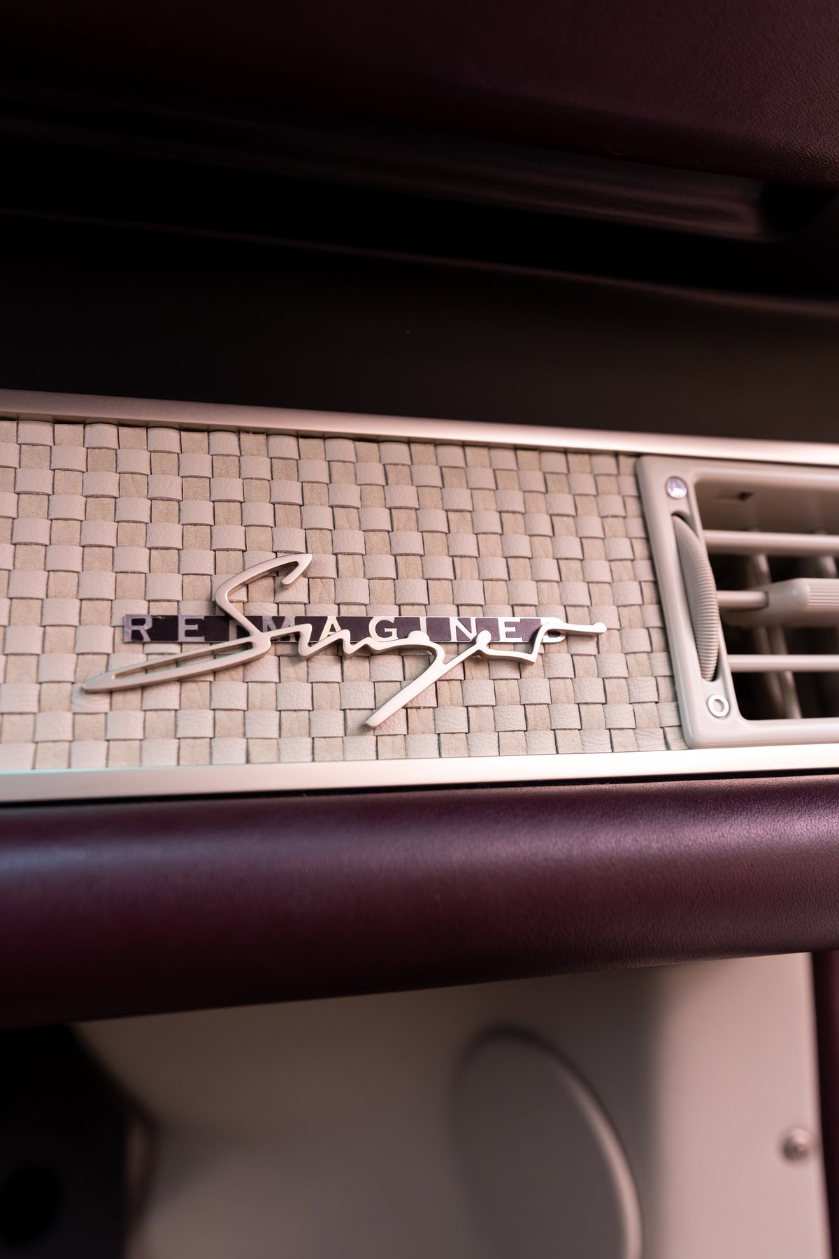 1990 Singer Porsche 911 in Aubergine Metallic, "Reimagined" badging on woven trim.
