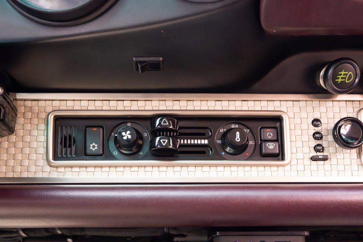 Interior shot of a 1990 Singer Porsche 911's climate control panel with metallic weave trim.