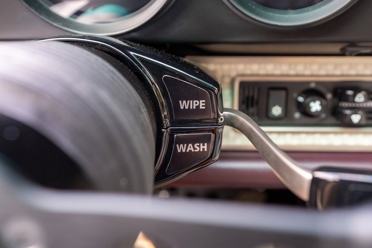 Close-up of a 1990 Singer Porsche 911 steering column controls, with "WIPE" and "WASH" buttons visible.
