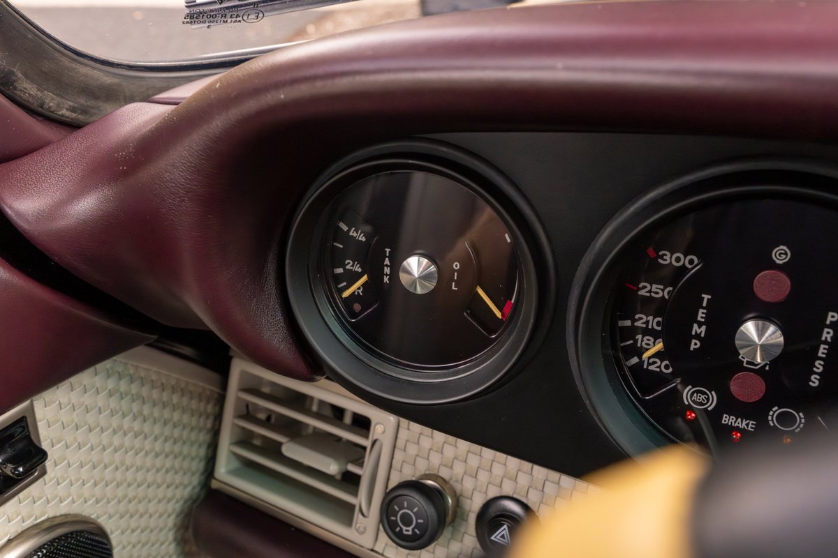 Singer 911 dashboard detail: aubergine metallic interior trim, oil temp gauge, and other classic gauges.