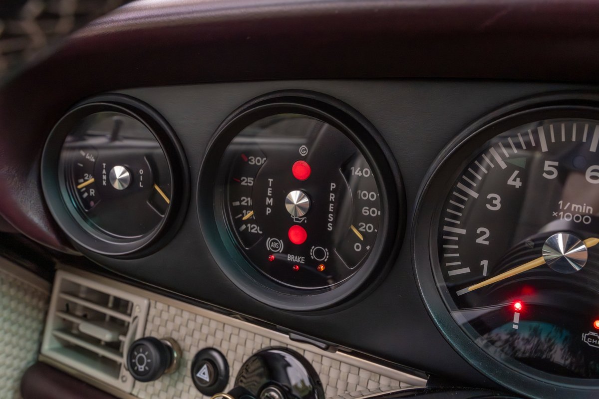 Close up of a 1990 Singer Porsche 911 dashboard with aubergine metallic interior trim.