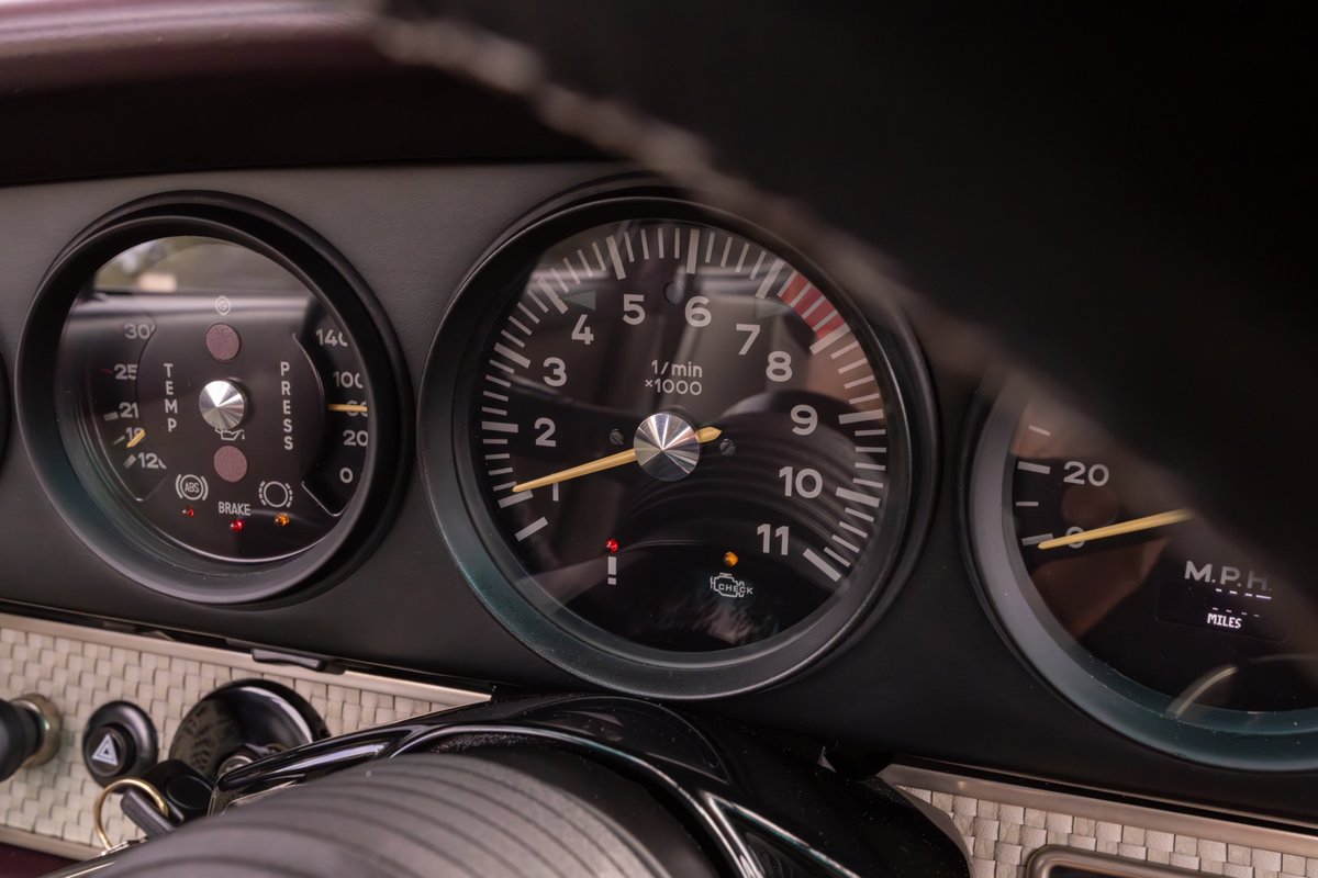 Close-up of a 1990 Singer Porsche 911 dashboard, showing tachometer, oil pressure, and speed gauges.