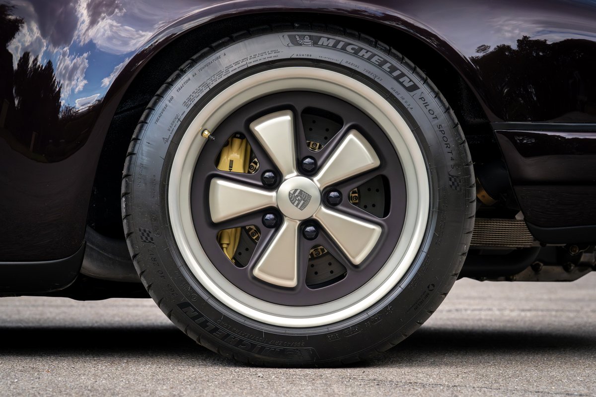 Aubergine metallic 1990 Singer Porsche 911 wheel with gold brake calipers.