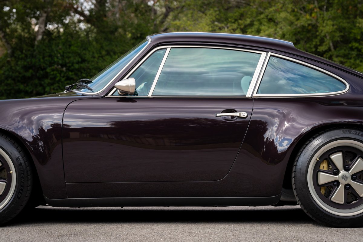 1990 Singer Porsche 911 coupe in Aubergine Metallic, side profile. Chrome trim and Fuchs-style rims visible.