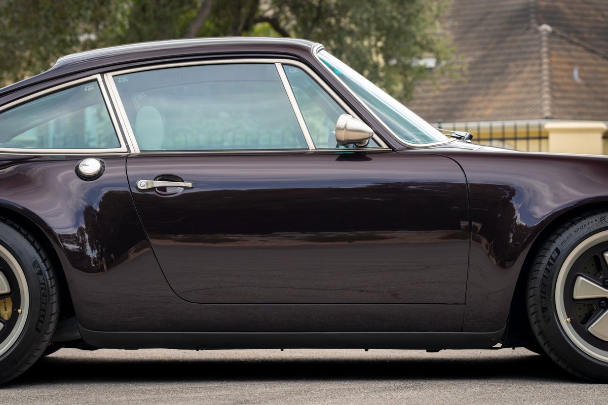 Aubergine metallic 1990 Singer Porsche 911 coupe, side profile, chrome trim, classic Fuchs rims.