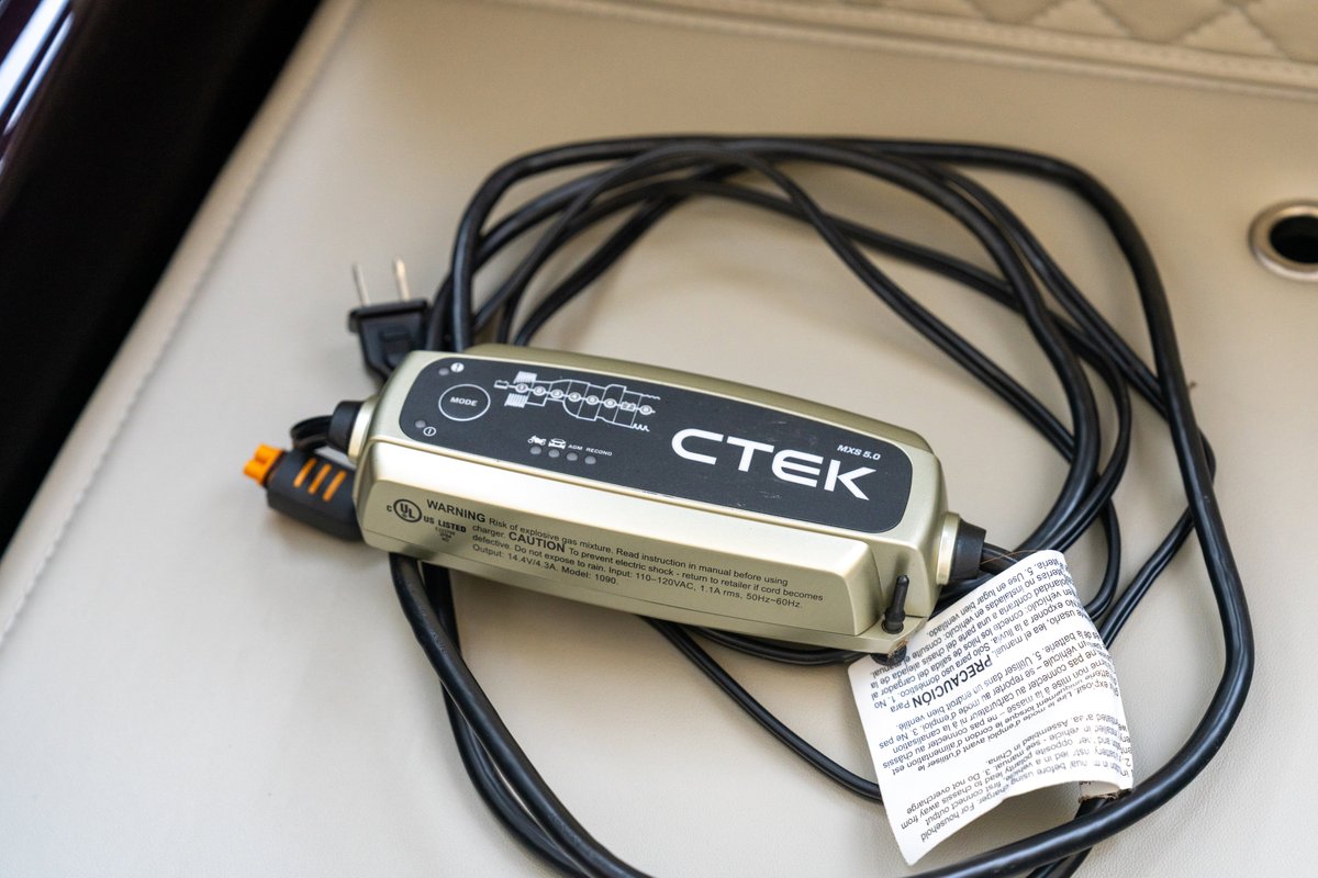 CTEK MXS 5.0 battery charger with cables on a leather seat, hinting at a 1990 Porsche 911.