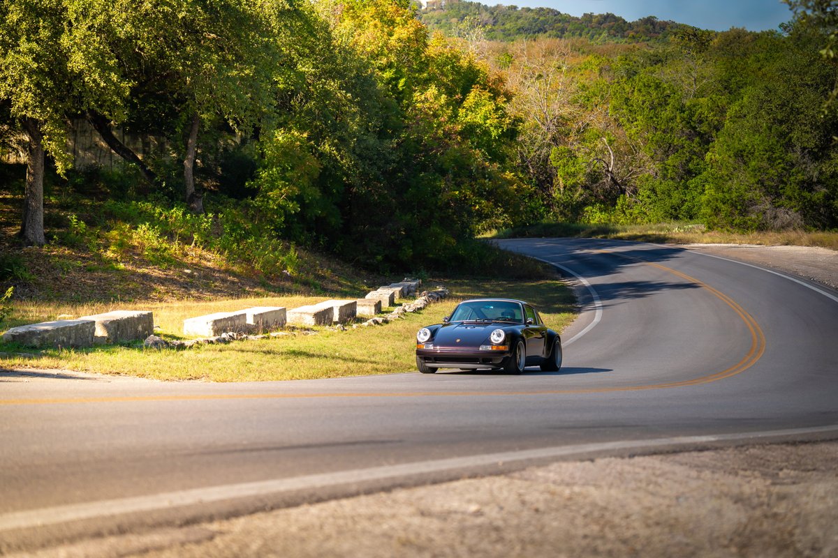 Aubergine Metallic 1990 Singer 911 on a winding road, showcasing its classic lines and subtle trim.