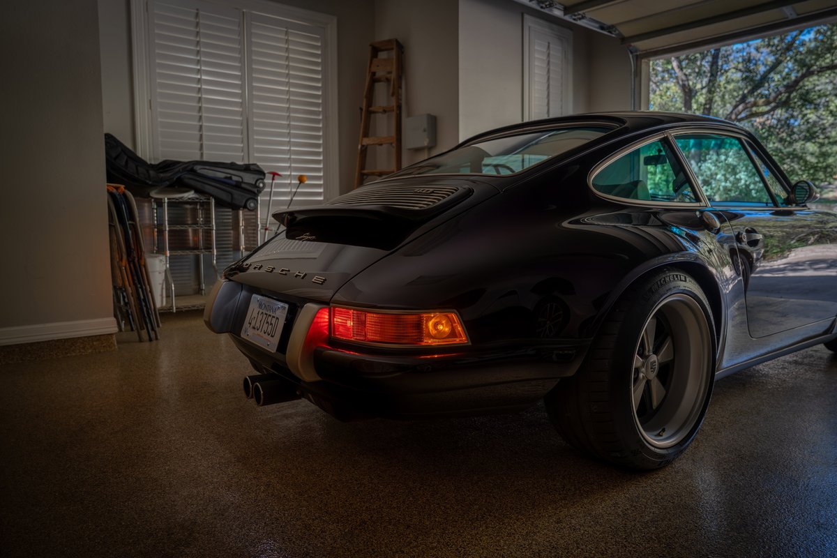 Black 1990 Singer Porsche 911 with Fuchs rims and green tinted windows.
