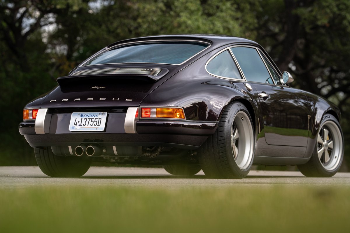 Aubergine metallic 1990 Singer 911 rear quarter view, showing silver rims, dual exhaust, and ducktail spoiler.