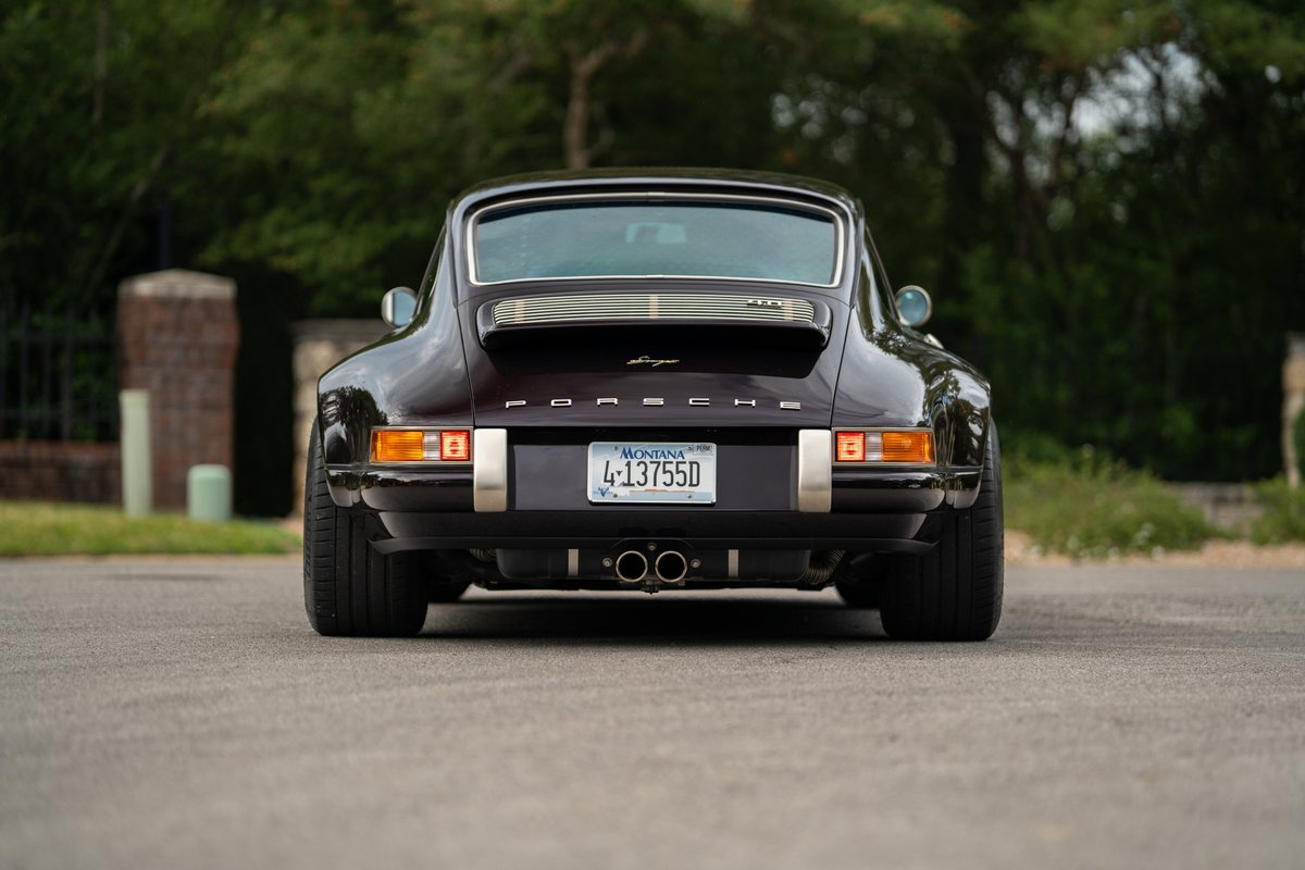 Aubergine metallic 1990 Singer Porsche 911 rear view with chrome trim and dual exhaust.