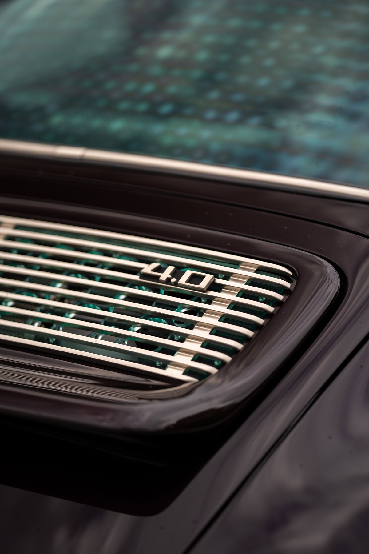 Close-up of a Singer 911 "4.0" badge on aubergine metallic bodywork.
