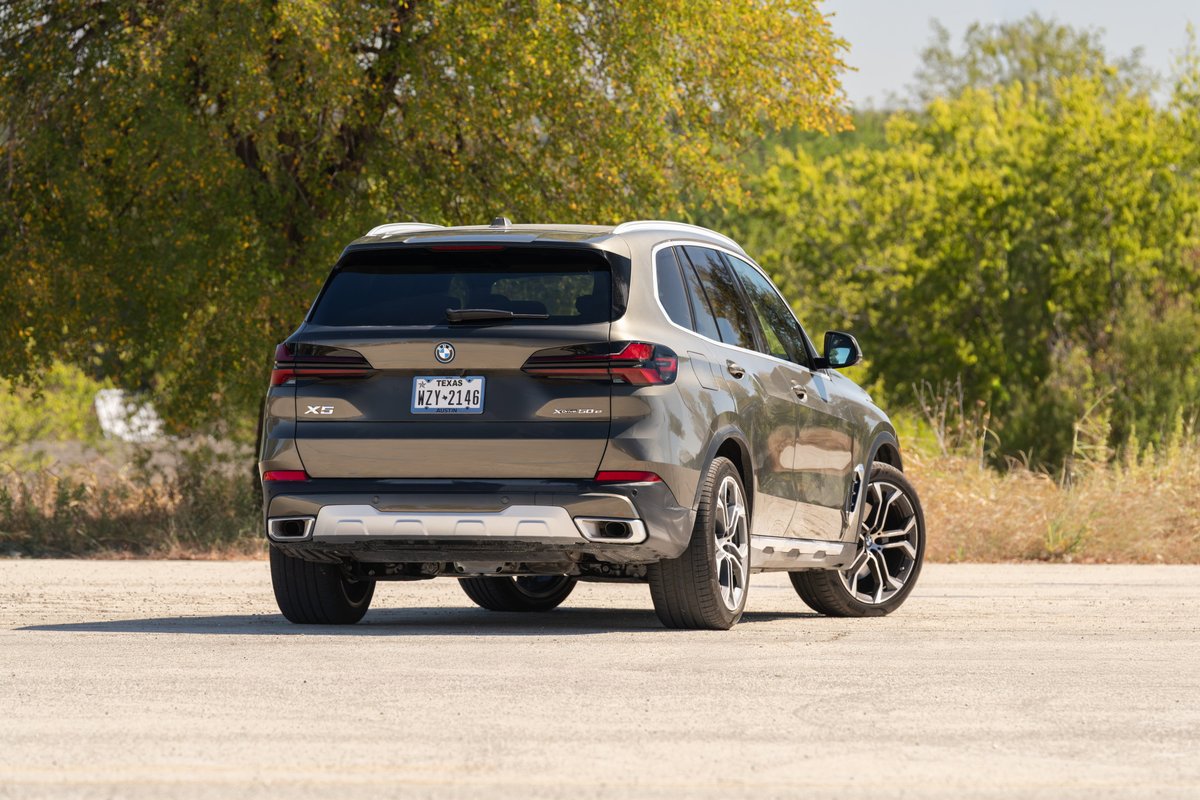 2026 BMW X5 in Manhattan Green, featuring black and silver multi-spoke rims and chrome exhaust tips.