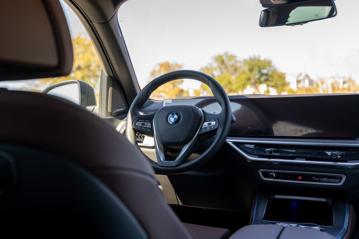 2026 BMW X5 interior, Manhattan Green, driver's perspective, black leather steering wheel.