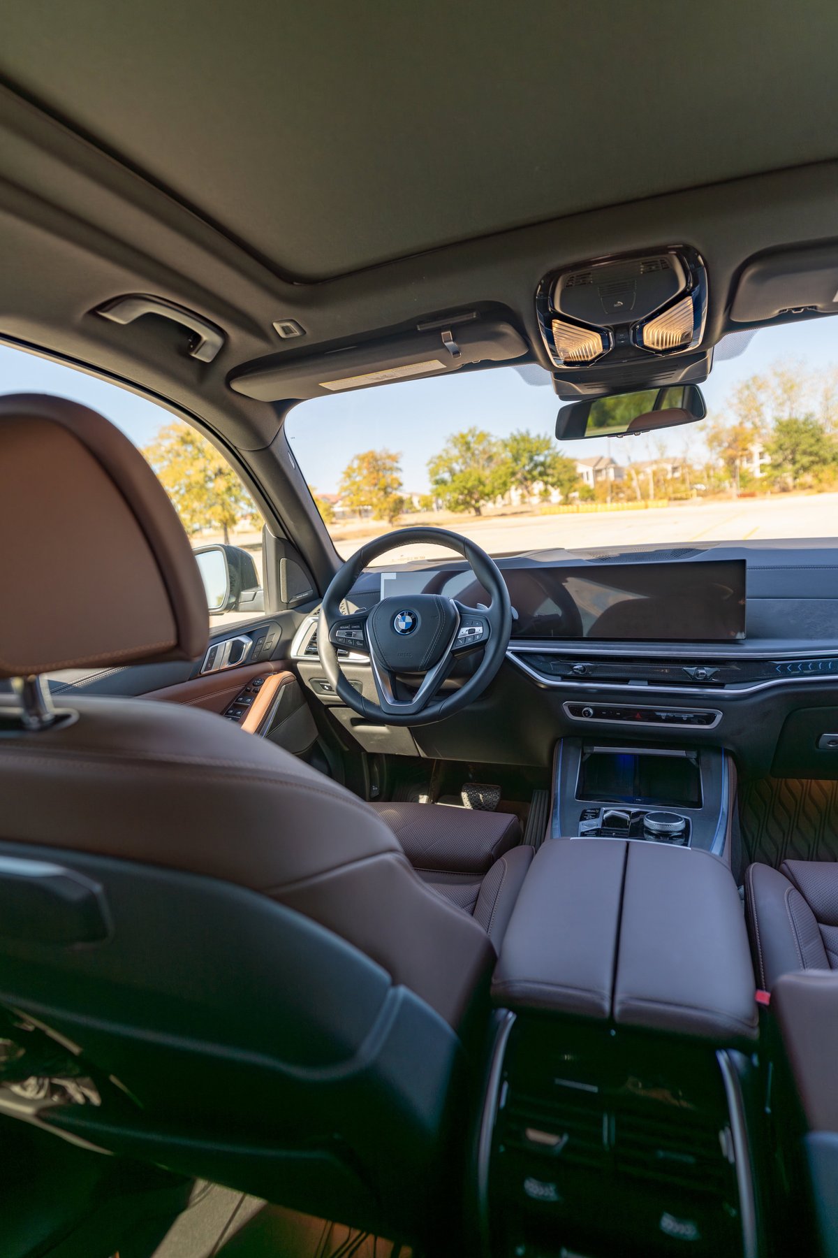 2026 BMW X5 interior with Manhattan Green exterior, featuring brown leather seats and a panoramic sunroof.