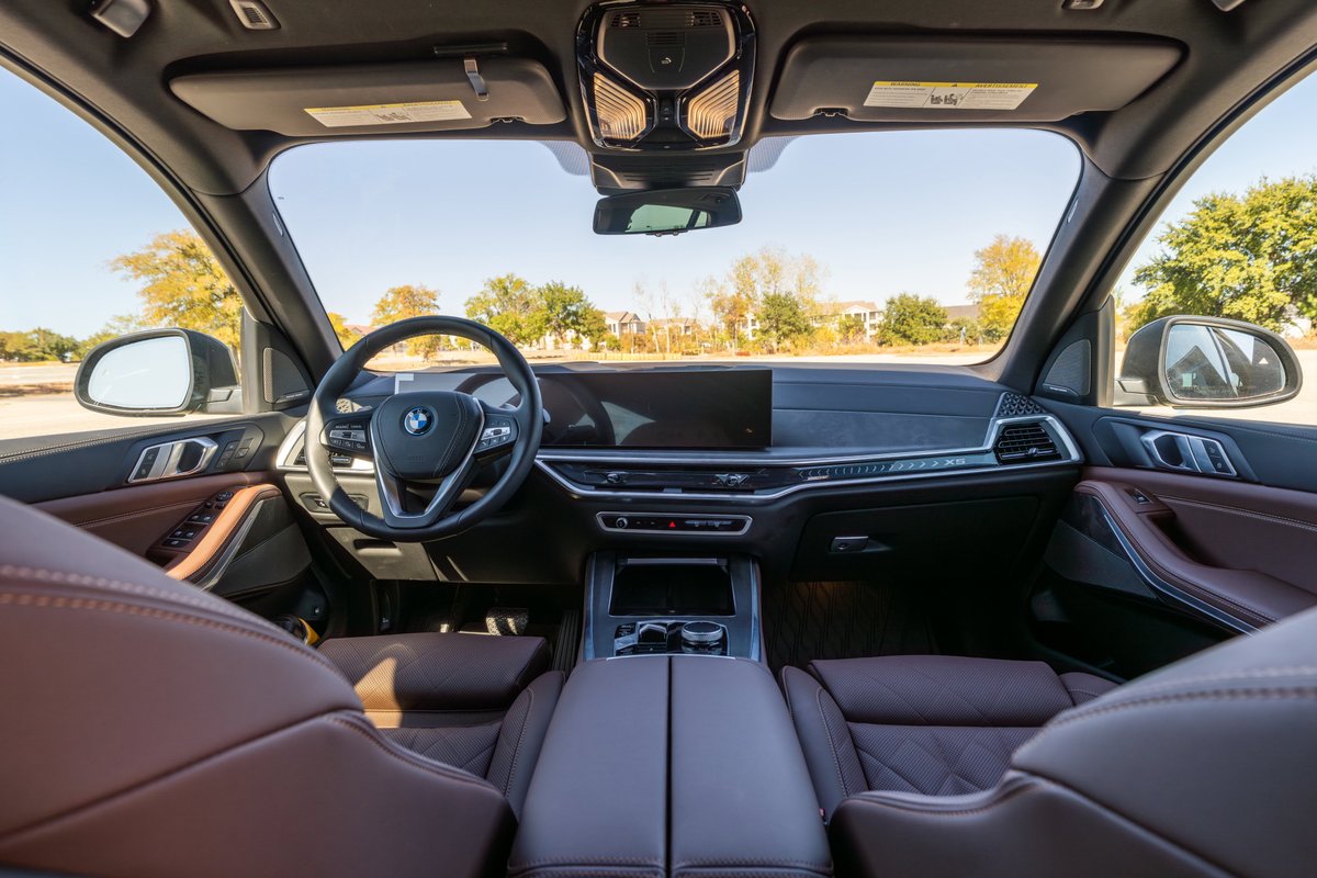 Interior view of a 2026 BMW X5 in Manhattan Green, featuring quilted brown leather trim.