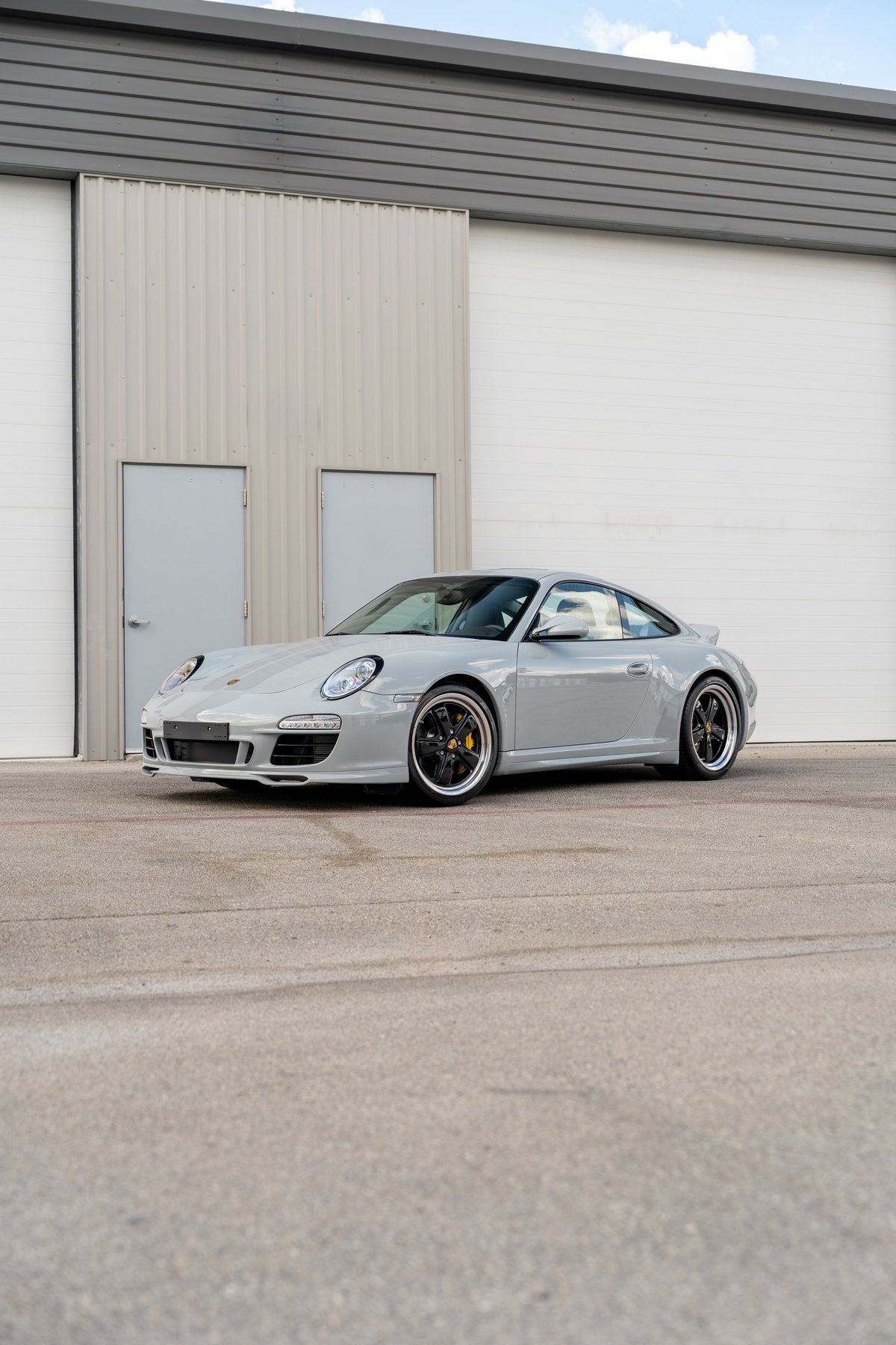 2010 Porsche 911 Sport Classic in light grey with black rims and yellow brake calipers.