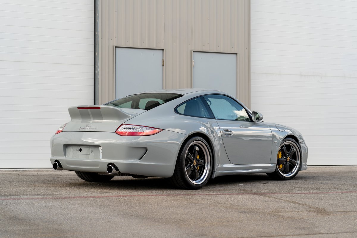 Rear 3/4 view of a 2010 Porsche 911 Sport Classic in primer gray with black multi-spoke rims and yellow brake calipers.