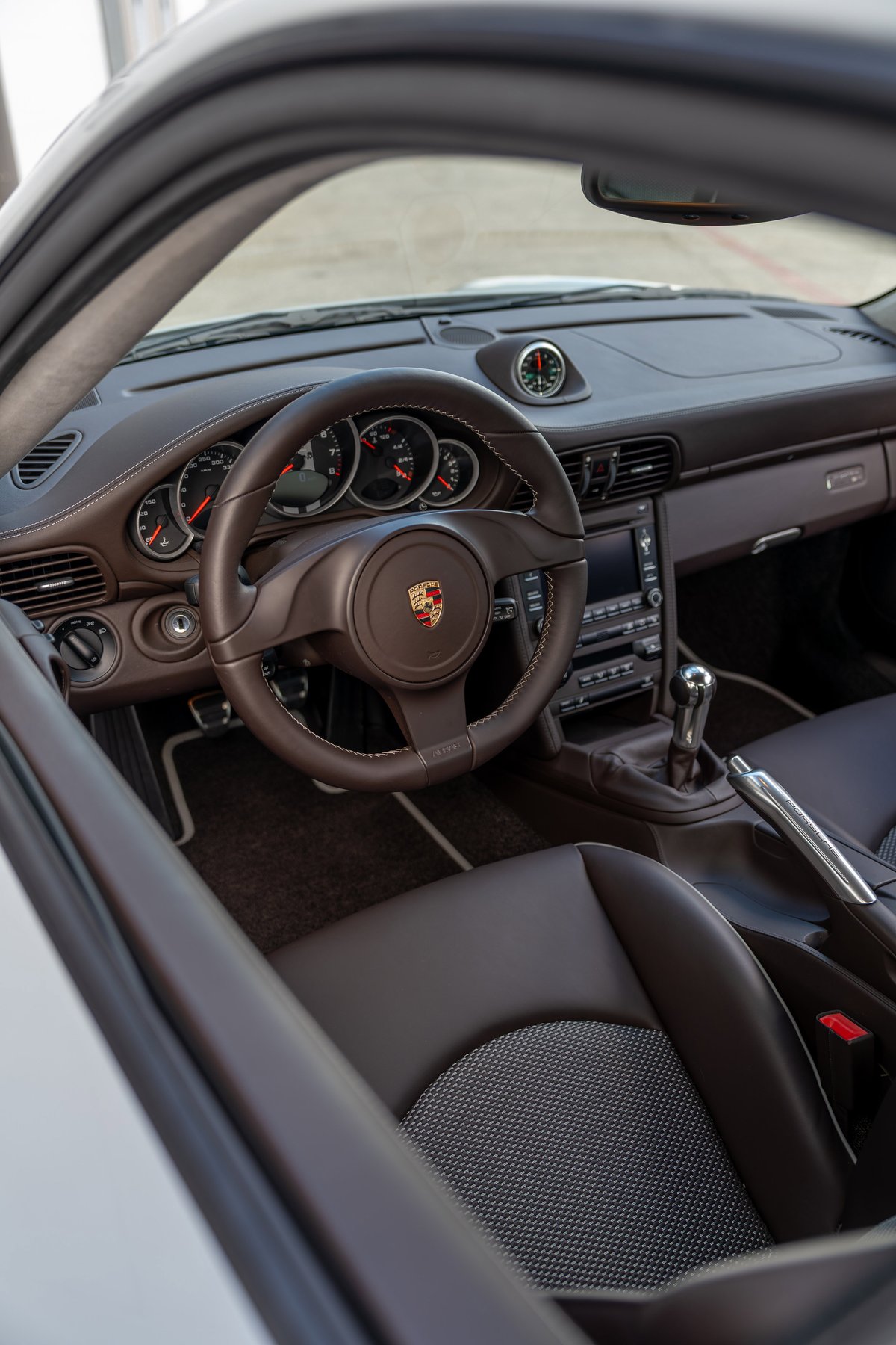 2010 Porsche 911 Sport Classic interior with brown leather trim and Porsche crest steering wheel.