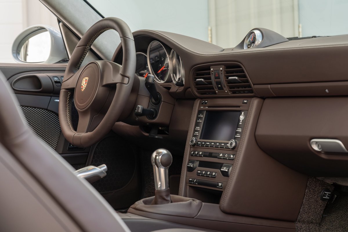 2010 Porsche 911 Sport Classic interior: brown leather trim, manual shifter, touchscreen.