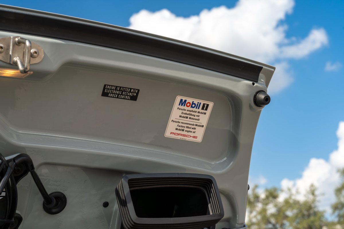 Close-up of the engine bay lid of a grey 2025 Porsche 911 Sport Classic, showing Mobil 1 stickers.
