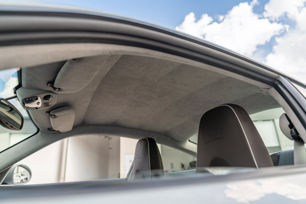 Interior of a Porsche 911 Sport Classic, showing gray Alcantara headliner and embossed headrests.