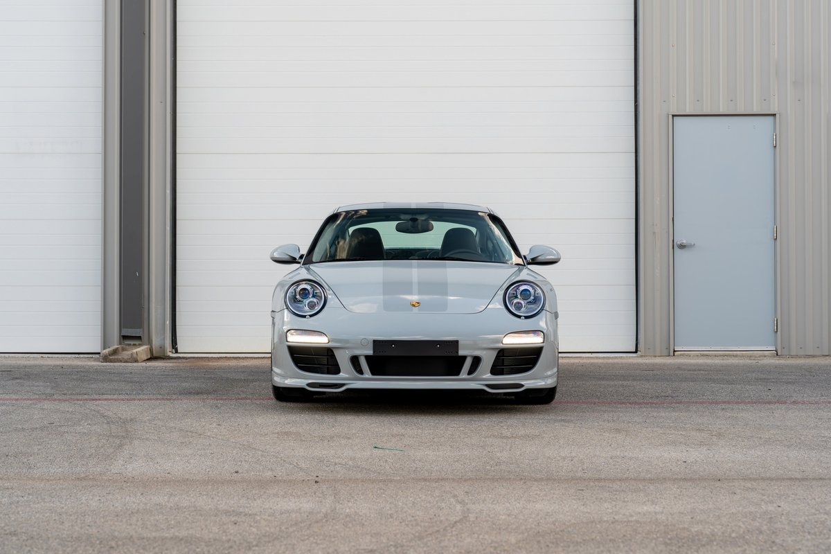 Front view of a grey 2010 Porsche 911 Sport Classic with racing stripes and silver rims.