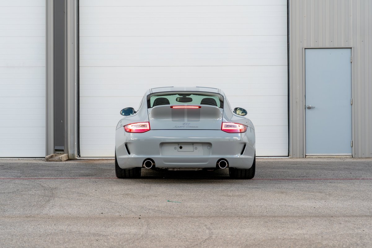 Rear view of a grey 2010 Porsche 911 Sport Classic with a prominent rear wing and dual exhaust tips.