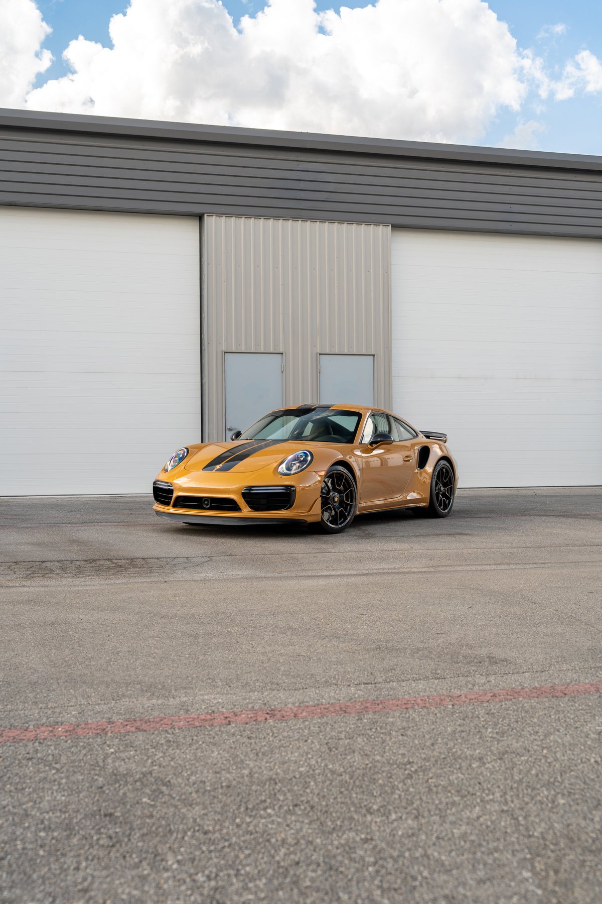 2018 Porsche 911 Turbo S Exclusive Series in Golden Orange Metallic with black racing stripes, black rims.